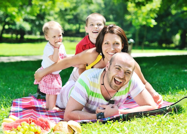 Glückliches junges Paar mit ihren Kindern haben Spaß am schönen Park im Freien in der Natur