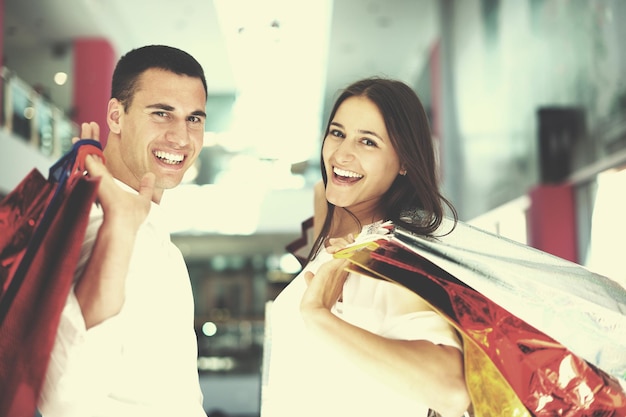 glückliches junges Paar mit Taschen im Einkaufszentrum
