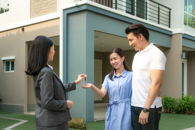 Glückliches junges Paar nimmt Schlüssel neues großes Haus vom Immobilienmakler