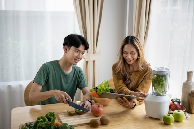 Glückliches junges Paar Vegetarier, die zu Hause gesunde Bio-Getränke in der Küche zubereiten