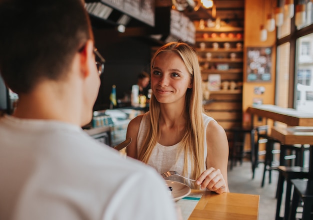 Glückliches junges paar verliebt sich mit einem schönen date in einer bar oder einem restaurant. sie erzählen einige geschichten über sich selbst, trinken tee oder kaffee und essen salat und suppe.