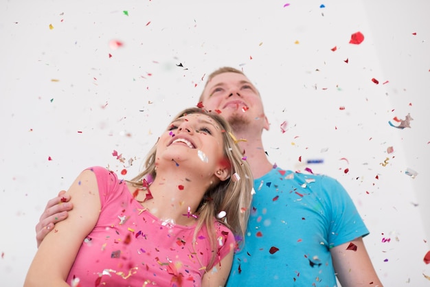 glückliches junges romantisches verliebtes paar feiert und bläst konfetti-dekorationen bei neujahrs- und charismas-party