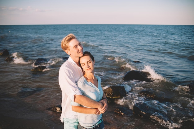 Glückliches junges verliebtes Paar gegen das Meer spazieren am Strand gegen den blauen Himmel und amüsieren sich am Sommertag Zweisamkeit Liebe Familie