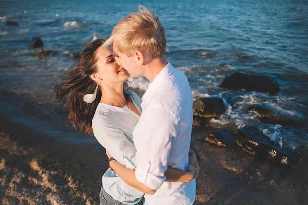 Glückliches junges verliebtes Paar gegen das Meer spazieren am Strand gegen den blauen Himmel und amüsieren sich am Sommertag Zweisamkeit Liebe Familie