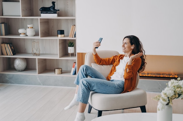 Glückliches kaukasisches Mädchen hat am Wochenendmorgen zu Hause einen Videoanruf Junge Frau benutzt Airpods