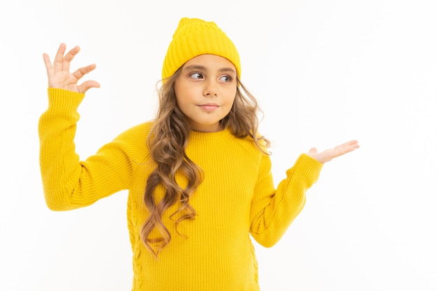 Glückliches kaukasisches Mädchen im gelben Hut und im Kapuzenpulli zeigt ein wenig lokalisiert auf weißem Hintergrund