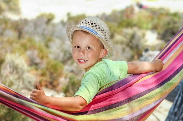 Glückliches Kind am Meer auf Hängematte