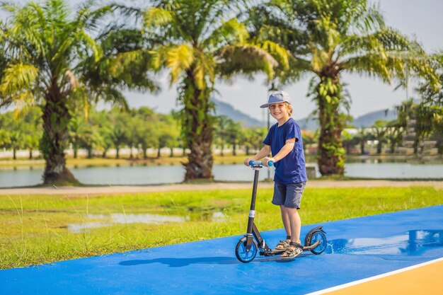 Glückliches Kind auf Tretroller auf dem Basketballplatz Kinder lernen, Rollbrett kleiner Junge zu skaten