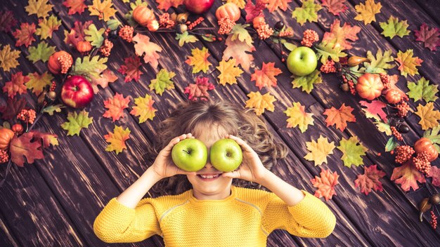 Glückliches Kind, das auf Herbstblättern liegt