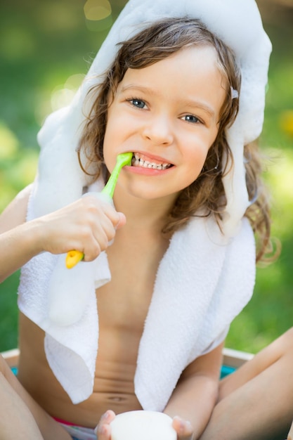 Glückliches Kind, das draußen auf grünem Gras im Frühlingsgarten badet