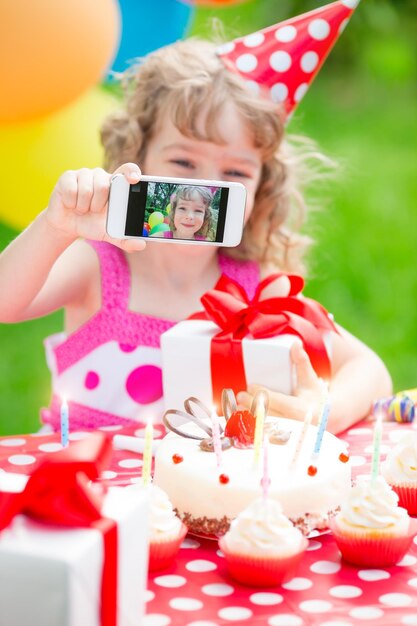 Glückliches Kind, das Geburtstag feiert Kind, das Spaß im Frühlingsgarten hat