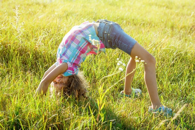 Glückliches Kind, das Handstand im Sommerpark tut