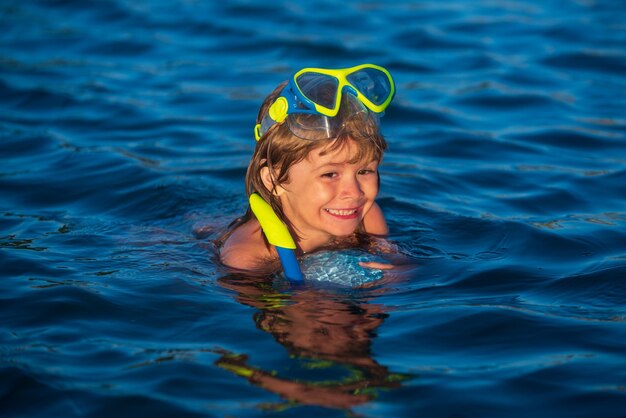 Glückliches Kind, das im Meer spielt, Junge, der sich am Strand im Sommerurlaub amüsiert