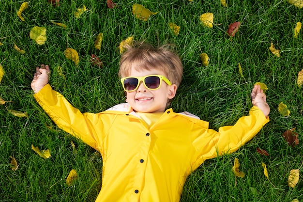 Glückliches Kind, das Spaß im Freien im Herbstpark hat