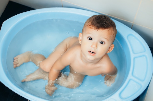 Glückliches Kind, ein Junge badet in einem Bad sehr süß