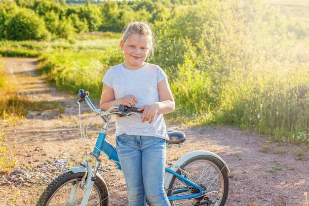 Glückliches Kind Fahrrad fahren. Junges Mädchen auf Fahrrad im sonnigen Sommerpark. Gesunde Schulkinder Sommeraktivität. Kinder spielen und Radfahren im Freien