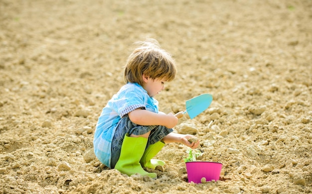 Glückliches Kind Gärtner Botanischer Arbeiter Frühlingssaison Gesundheit und Ökologie Tag der Erde neues Leben Sommerbauernhof Ökologie Leben Ökobauernhof Mensch und Natur kleines Kind, das einen Blumenarbeitsplatz pflanzt