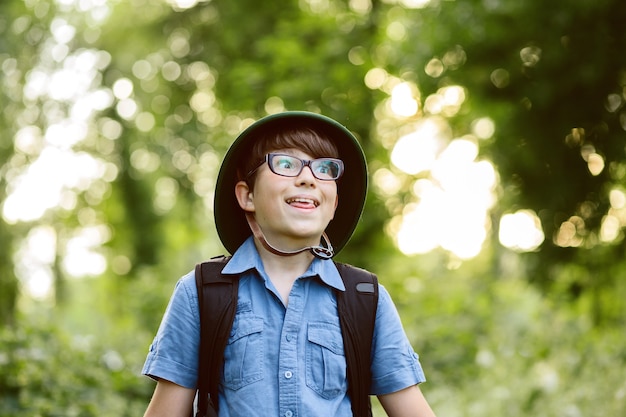 Glückliches Kind geht mit Rucksack in der Sommernatur wandern