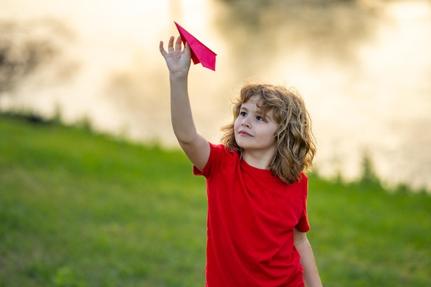 Glückliches Kind hält Papierflugzeuge Spielzeugflugzeug in Kindern Hände im Freien glücklicher Junge lehnt und wirft Sie