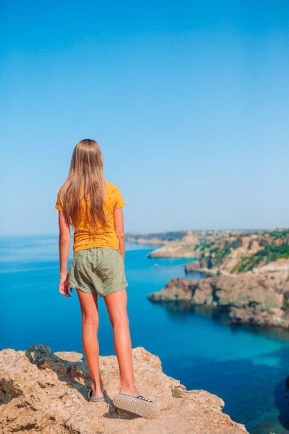 Glückliches Kind im Freien am Rande der Klippenküste