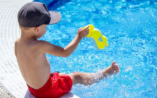 Glückliches Kind im Pool, das mit einer Wasserpistole spielt.