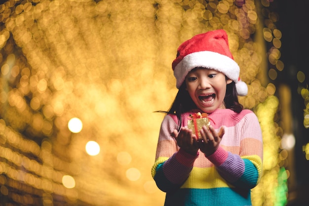 Glückliches Kind in Santa Red Hat mit Weihnachtsgeschenken. Weihnachtszeit.