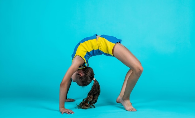 Foto glückliches kind in sporttrainingskleidung trainiert akrobatik