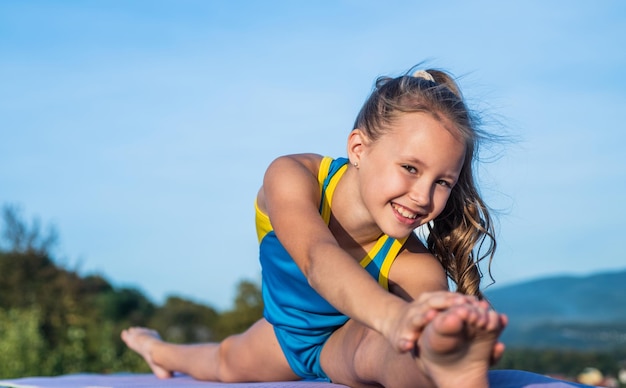 Glückliches Kind in Sporttrainingskleidung trainiert im Freien beim Aufwärmen