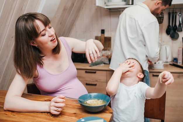 Glückliches Kind isst Nudeln in der Küche mit ihrer Familie