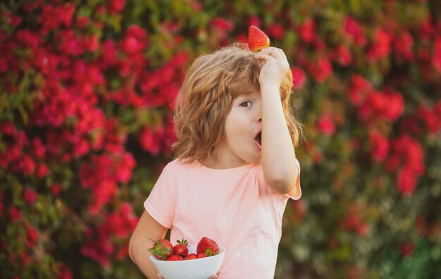 Glückliches Kind, Junge isst Erdbeere. Schönes, lustiges Kind, das Erdbeeren isst