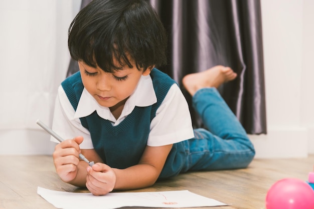 Glückliches Kind Junge Kindergarten Zeichnung auf peper Lehrerausbildung im Innenraum zu Hause