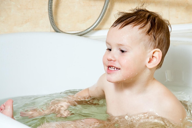 Glückliches Kind kleines Mädchen badet in einem Schaumbad wäscht ihr Gesicht Das Konzept der Kinderhygiene Freude spritzt Lachen viel Spaß Familienlebensstil