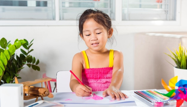 Glückliches Kind kleines Mädchen bunte Zeichnung rosa Herz auf weißem Papier
