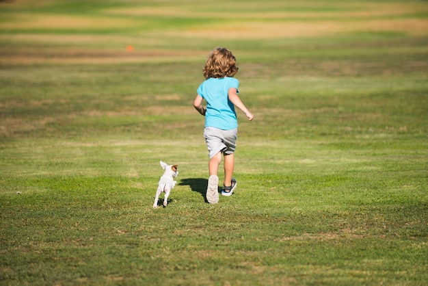 Glückliches Kind läuft mit einem Hund im Freien, der Hund läuft