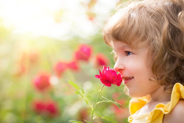 Glückliches Kind mit Blume draußen im Frühlingsgarten