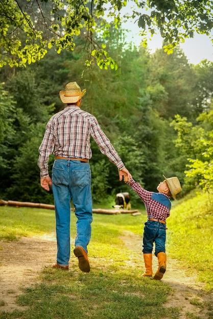 Glückliches Kind mit Cowboy-Elternteil in der Natur im Feld