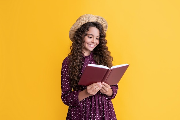 Glückliches Kind mit krausem Haar las Buch auf gelbem Hintergrund