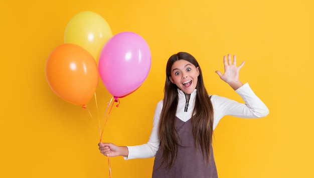 Glückliches Kind mit Partyheliumballons auf gelbem Hintergrund