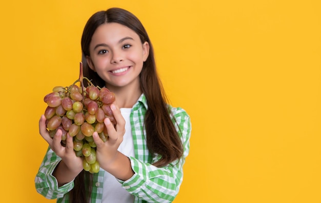 Glückliches Kind mit reifen Trauben Traubenbündel auf gelbem Hintergrund