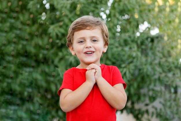 Glückliches Kind mit rotem T-Shirt im Garten