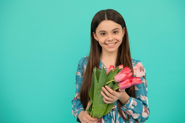 Glückliches Kind mit Tulpen Mütter oder Kinder zum Frauentag halten Blumen für den 8. März Teenager-Mädchen mit Frühlingsblumenstrauß auf blauem Hintergrund Blumen vorhanden Kopierraum