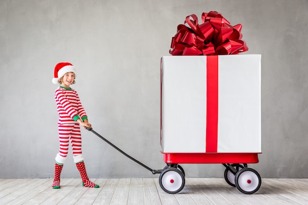 Glückliches Kind mit Weihnachtsgeschenk. Kind hat Spaß zu Hause