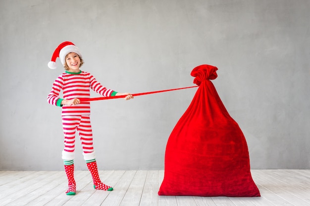 Glückliches Kind mit Weihnachtstüte Kind hat Spaß zu Hause