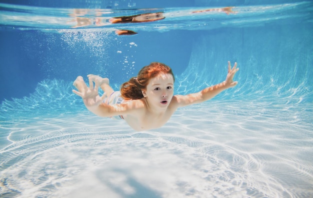 Glückliches Kind schwimmt im Pool unter Wasser Aktives Kind schwimmt unter Wasser spielend und hat Spaß Kinder w