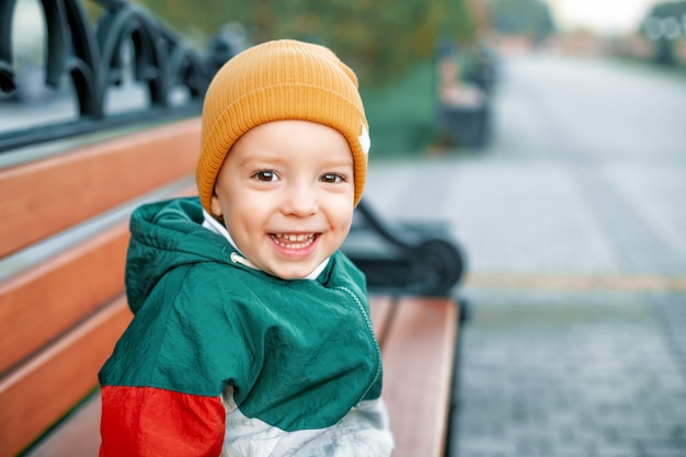 Glückliches Kind sitzt auf einer Bank mit einem orangefarbenen Bennie bench