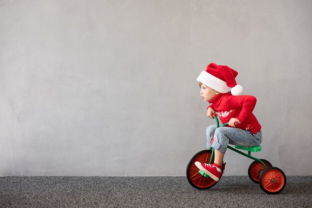 Glückliches Kind trägt Weihnachtskostüm Kind reitet Fahrrad