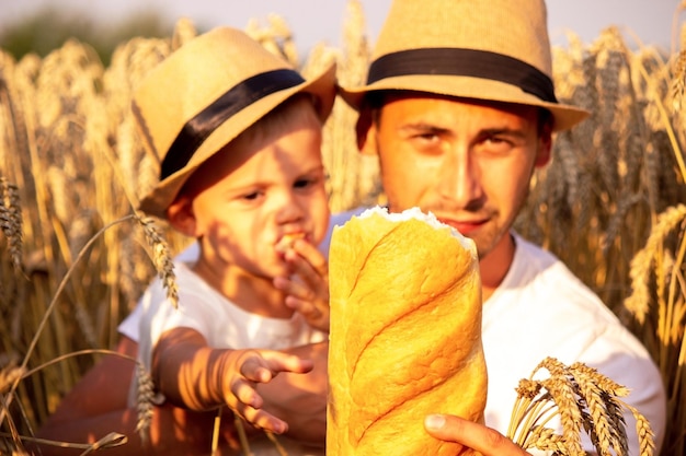 Glückliches Kind und Vater auf dem Feld des reifenden Weizens Junge und Vater reisen über das Feld Chi...