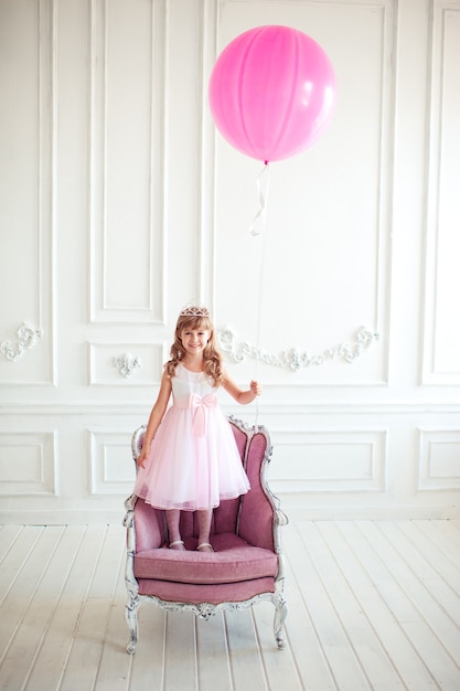 Glückliches Kindermädchen, das großen rosa Ballon hält