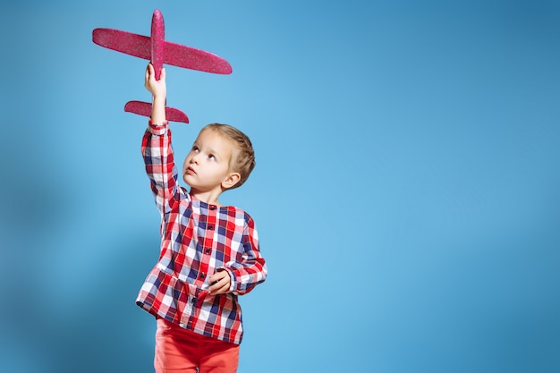 Glückliches Kindermädchen, das mit Spielzeugflugzeug spielt. Der Traum, Pilot zu werden.