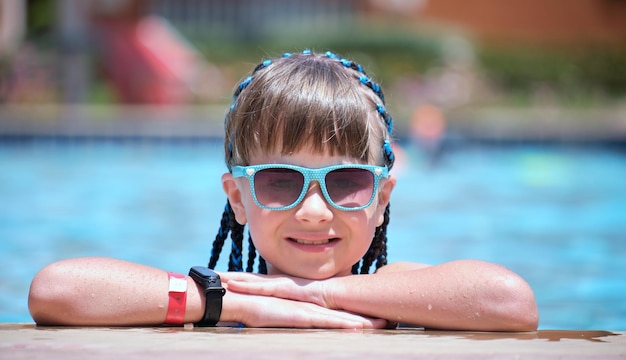 Glückliches Kindermädchen, das sich an einem sonnigen Sommertag am Swimmingpool entspannt